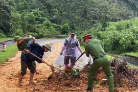 Cán bộ, chiến sỹ công an các xã của tỉnh Tuyên Quang cùng người dân san gạt đất đá, khơi thông tuyến đường bị sạt lở do mưa lũ. (Ảnh: TTXVN phát)