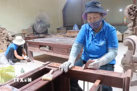 Những người thợ tỷ mỉ, cẩn thận đánh giấy giáp cho gỗ lỳ, bóng. (Ảnh: Thanh Thương/TTXVN)