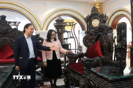 Đại diện Công ty Đồ gỗ mỹ nghệ Nam Thắng, phường Đồng Nguyên, tỉnh Bắc Ninh (bên trái) giới thiệu các mặt hàng gỗ của gia đình. (Ảnh: Thanh Thương/TTXVN)