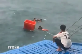 Thủy thủ và thuyền viên cứu ngư dân gặp nạn trên biển. (Ảnh: TTXVN phát)