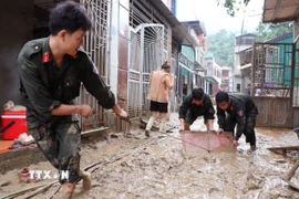 Các chiến sỹ đồn biên phòng Cửa khẩu Quốc tế Thanh Thủy (Tuyên Quang) giúp người dân dọn vệ sinh sau lũ. (Ảnh: Đức Thọ/TTXVN)