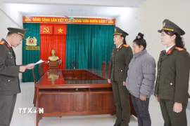 Cán bộ cơ quan An ninh điều tra công an tỉnh Điện Biên đọc Quyết định khởi tố bị can và Lệnh cấm đi khỏi nơi cư trú đối với Vì Thị Tiện. (Ảnh: TTXVN phát)