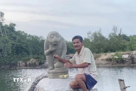 Ông Dương Đình Lục và tượng Khỉ Hanuman do ông trục vớt được. (Ảnh: TTXVN phát)