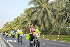 Du khách trải nghiệm "du lịch xanh" dưới tán dừa trên các cung đường phường An Hội, tỉnh Vĩnh Long. (Ảnh: Chương Đài/TTXVN)