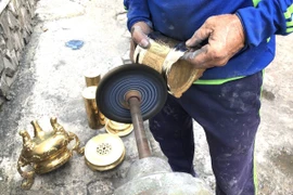 Những hoa văn rồng phượng tinh xảo trên nắp lư hay chân đèn phải được làm kỹ bằng tay để đảm bảo độ sáng đều. (Ảnh: Nguyễn Văn Việt/TTXVN)