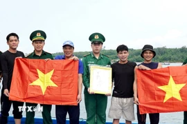 Lực lượng Biên phòng tặng cờ Tổ quốc và ảnh Bác Hồ cho ngư dân tham gia khai thác hải sản xa bờ. (Ảnh: Lê Phước Ngọc/TTXVN)