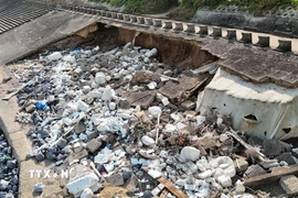 Đoạn kè ven biển dài khoảng 60m bị sóng biển khoét sâu vào trong, lộ ra xi măng, cốt thép, đất... (Ảnh: Thanh Thủy/TTXVN)