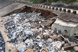 Đoạn kè ven biển dài khoảng 60m bị sóng biển khoét sâu vào trong, lộ ra xi măng, cốt thép, đất... (Ảnh: Thanh Thủy/TTXVN)