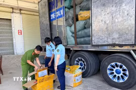 Lực lượng chức năng kiểm đếm hàng hoà nghi giả mạo nhãn hiệu thời trang nổi tiếng. (Ảnh: TTXVN phát)