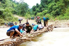 Dân bản được huy động tối đa thực hiện việc làm cầu khi nước suối Nậm Ngân đang còn dâng cao. (Ảnh: TTXVN phát).