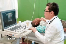Bác sỹ Tôn Thanh Trà, Giám đốc Bệnh viện Chợ Rẫy - Phnom Penh trực tiếp thăm khám, siêu âm một trường hợp bệnh nhân bệnh nặng, tiếp nhận phẫu thuật miễn phí tại bệnh viện. (Ảnh: Quang Anh/TTXVN)