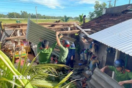 Lực lượng Công an tỉnh Gia Lai giúp người dân dựng lại mái nhà. (Ảnh: Sỹ Thắng/TTXVN)