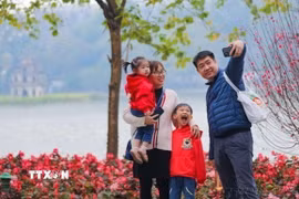 Một gia đình cùng nhau ghi lại khoảnh khắc của mùa Xuân bên hồ Gươm. (Ảnh: Thanh Tùng/TTXVN)