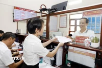 Cán bộ trao trả kết quả thủ tục hành chính cho người dân tại Trung tâm hành chính công xã. (Ảnh: Thái Thuần/TTXVN)