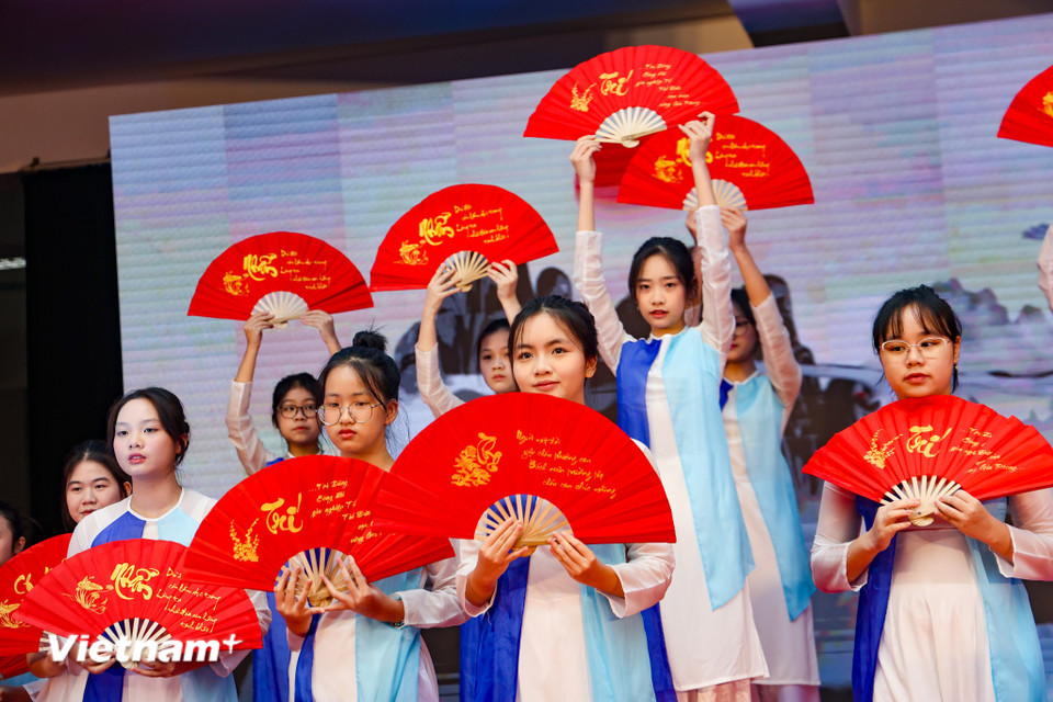 Các em học sinh trong trang phục áo dài, biểu diễn tiết mục múa thư pháp. (Ảnh: Minh Hiếu/Vietnam+)