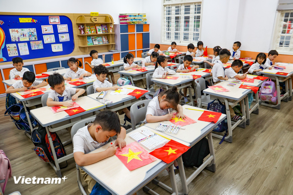 Các em học sinh lớp 1A1 được cô giáo dạy tập vẽ cờ Tổ quốc. (Ảnh: Minh Hiếu/Vietnam+)