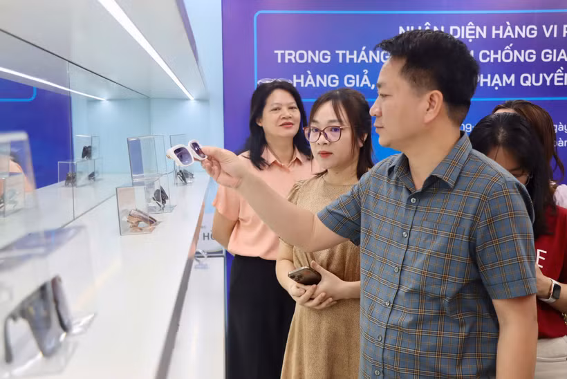 Lãnh đạo Cục Quản lý và Phát triển thị trường trong nước hướng dẫn nhận biết hàng không chính hãng. (Ảnh: PV/Vietnam+)