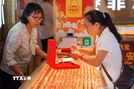 Khách hàng chọn mua trang sức vàng tại một cửa hàng ở tỉnh Quý Châu, Trung Quốc. (Ảnh: THX/TTXVN)