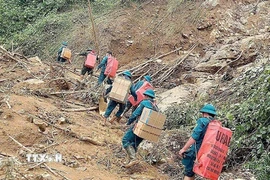 Các lực lượng cõng nhu yếu phẩm cần thiết vượt núi, băng rừng, lội suối vào tiếp tế cho các hộ xã biên giới Yên Nhân (Thanh Hóa) bị sạt lở cô lập. (Nguồn: TTXVN phát)