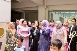 Phu nhân Nguyễn Thị Thanh Nga (áo dài, hàng trước) nghe giới thiệu về Trung tâm. (Nguồn: TTXVN phát)