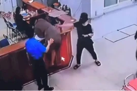 Người đàn ông chồm lên quầy làm thủ tục hành hung nhân viên bệnh viện. (Nguồn: Ảnh chụp màn hình)