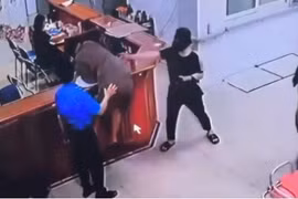 Người đàn ông chồm lên quầy làm thủ tục hành hung nhân viên bệnh viện. (Nguồn: Ảnh chụp màn hình)