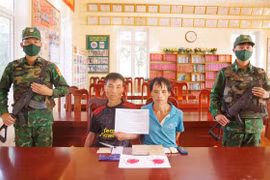Hai đối tượng cùng tang vật vụ án. (Ảnh: TTXVN phát)