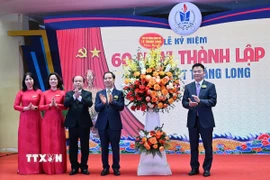 Phó Thủ tướng Chính phủ Lê Thành Long trao lẵng hoa tặng thầy và trò trường Trung học Phổ thông Thăng Long. (Ảnh: Nguyễn Cúc/TTXVN)