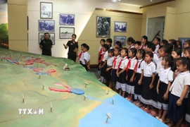 Học sinh trường Dongsavanh, huyện Sepon (Savannakhet, Lào) tham quan sa bàn ghi lại các trận đánh ác liệt của Liên minh chiến đấu Việt Nam-Lào. (Ảnh: Xuân Tú/TTXVN)