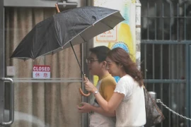 Người dân di chuyển trên đường phố trong gió lớn do ảnh hưởng của bão Wipha tại Trung Quốc. (Ảnh: THX/TTXVN)