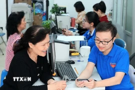 Đoàn viên thanh niên phường Hàng Bồ (quận Hoàn Kiếm, thành phố Hà Nội) hỗ trợ người dân thực hiện thủ tục hành chính công trên thiết bị điện thoại thông minh. (Ảnh: Phạm Hậu/TTXVN)
