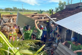 Lực lượng Công an tỉnh Gia Lai giúp người dân dựng lại mái nhà. (Ảnh: Sỹ Thắng/TTXVN)