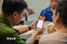 Tổ chuyển đổi số cộng đồng hướng dẫn người dân sử dụng ứng dụng định danh công dân trên môi trường kỹ thuật số (VNeID) có giá trị sử dụng thay thế các giấy tờ truyền thống. (Ảnh: Hoàng Hiếu/TTXVN)