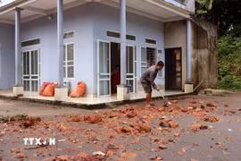 Người dân tranh thủ dọn dẹp đất đá, bùn đất để sớm khôi phục sinh hoạt. (Ảnh: Đức Thọ/TTXVN)
