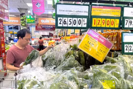 Người dân lựa chọn mua rau xanh nhãn riêng CoopSelect tại siêu thị Co.opmart trên đường Nguyễn Đình Chiểu, Thành phố Hồ Chí Minh. (Ảnh: Hương Giang/TTXVN)
