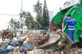 Xe thu gom rác và công nhân vệ sinh môi trường từ thành phố Hồ Chí Minh đến Khánh Hòa hỗ trợ thu gom rác trên bãi biển Nha Trang. (Ảnh: Phan Sáu/TTXVN)