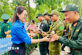 Tình nguyện viên trao nước uống cho các lực lượng làm nhiệm vụ. (Ảnh: TTXVN phát)