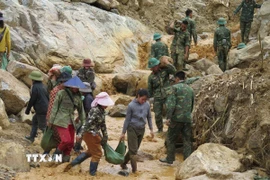 Người dân cùng các cán bộ, chiến sỹ Quân đoàn 34 triển khai công tác mở đường vào 5 thôn ở xã Ngọc Linh (Quảng Ngãi) bị cô lập do mưa lũ. (Ảnh: Dư Toán/TTXVN)