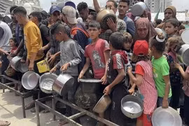 Người dân Palestine nhận thức ăn cứu trợ tại Dải Gaza. (Ảnh: IRNA/TTXVN)