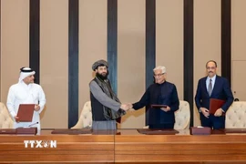 Bộ trưởng Quốc phòng Afghanistan Mullah Mohammad Yaqoob Mujahid và người đồng nhiệm Pakistan Khawaja Muhammad Asif trao đổi văn kiện sau lễ ký thỏa thuận ngừng bắn, tại Doha, Qatar, ngày 19/10/2025. (Nguồn: Reuters/TTXVN)
