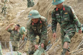 Cán bộ, chiến sỹ Quân đoàn 34 triển khai công tác mở đường vào các thôn bị cô lập do mưa lũ ở xã Ngọc Linh. (Ảnh: Dư Toán/TTXVN)