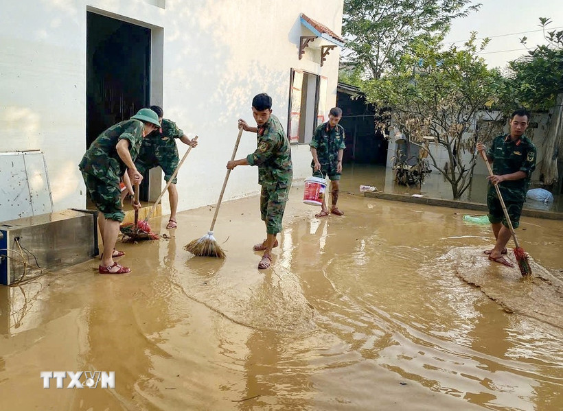Cán bộ chiến sỹ Trung đoàn 95 giúp người dân dọn dẹp khắc phục hậu quả lũ lụt. (Ảnh: Danh Lam/TTXVN)