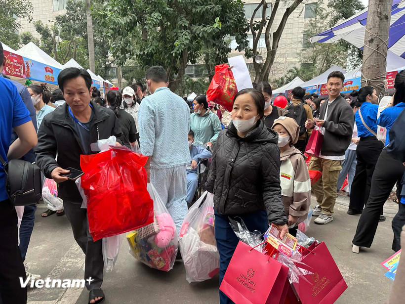 Gia đình các bệnh nhân nhi với những túi quà đầy đủ các mặt hàng phục vụ Tết. (Ảnh: PV/Vietnam+)