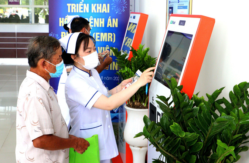 Nhân viên y tế hướng dẫn người dân đăng ký khám bệnh qua hệ thống kios tự động tại Bệnh viện Đa khoa Trà Vinh, tỉnh Vĩnh Long. (Ảnh: TTXVN)