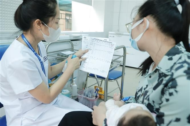 Nhân viên y tế hướng dẫn người dân về loại vaccine được tiêm, liều lượng tiêm và cách theo dõi, hướng dẫn sau khi tiêm. (Ảnh: Minh Quyết/TTXVN)