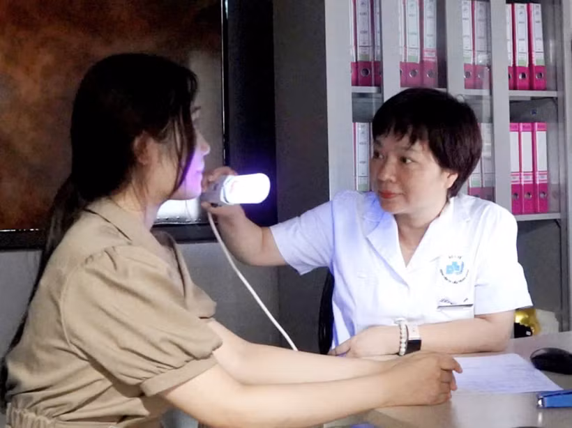Phó giáo sư Đỗ Thị Thu Hiền khám cho bệnh nhân bị bệnh bạch biến. (Ảnh: PV/Vietnam+)