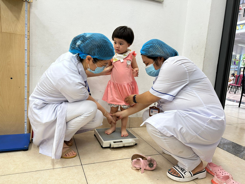 Nhân viên y tế đo chiều cao cho trẻ em. (Ảnh: PV/Vietnam+)