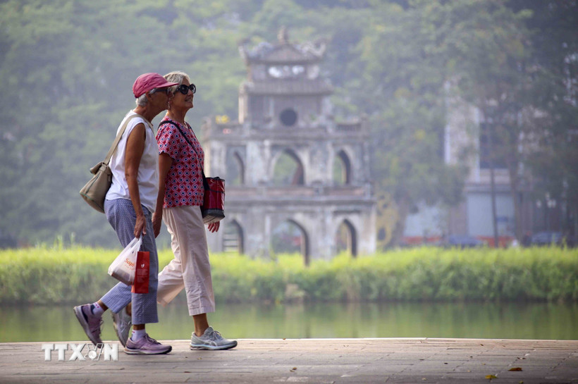 Du khách nước ngoài đi dạo bên hồ Hoàn Kiếm. (Ảnh: Tuấn Đức/TTXVN)