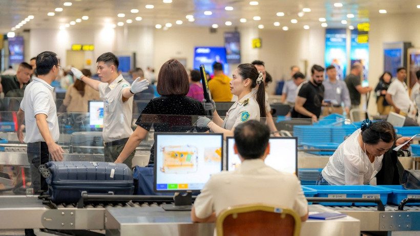 Nhân viên an ninh hàng không tại Sân bay Quốc tế Nội Bài kiểm tra hành khách qua cửa soi chiếu. (Ảnh: PV/Vietnam+)