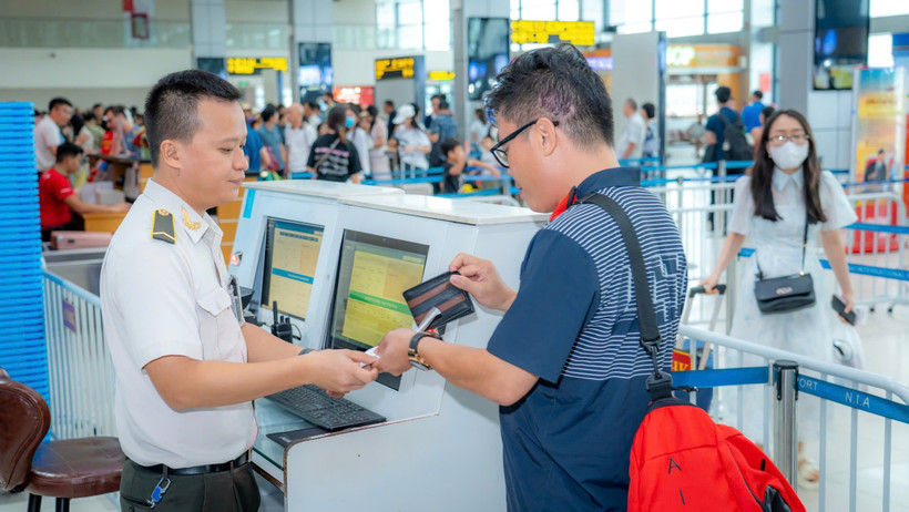 Nhân viên an ninh hàng không kiểm tra giấy tờ hành khách làm thủ tục lên máy bay. (Ảnh: PV/Vietnam+)